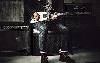 Rock musician playing white electric guitar with amplifiers