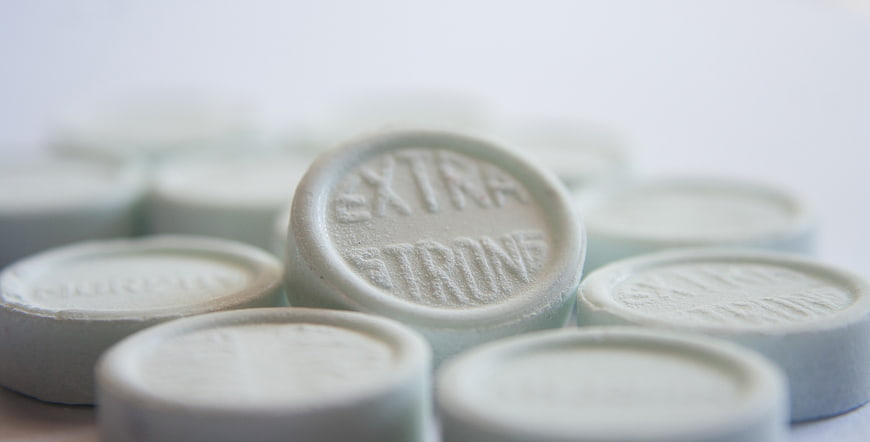 Close-up of white extra strong lozenges with embossed text on a clean surface