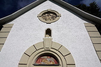 White chapel facade with religious sculpture and Ave Maria painting