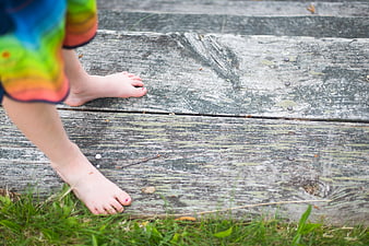 Child's bare feet on weathered wooden dock planks