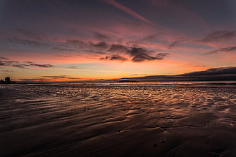 Dramatic Sunset Over Wet Sandy Beach with Ripples