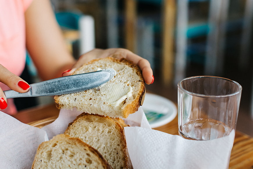 Close-up of hands buttering fresh bread slice