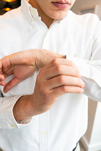Close-up of man adjusting white shirt cuff