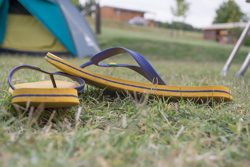 Yellow and Blue Flip Flops on Grass with Tent Background