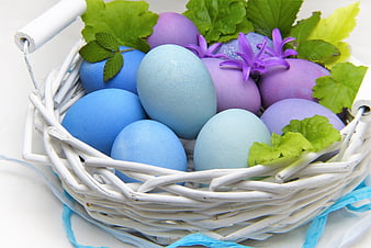 White wicker basket with blue and purple Easter eggs and spring flowers