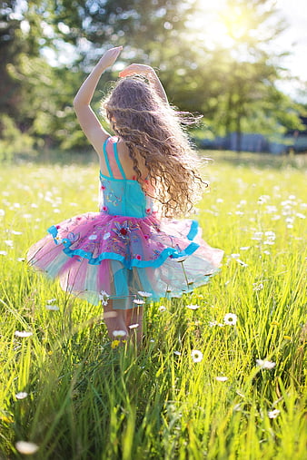 Little girl in colorful tutu dancing in a sunny meadow with daisies