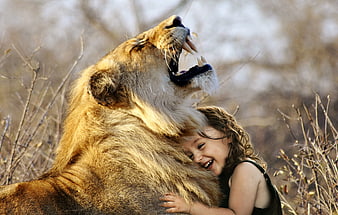 Little girl hugging roaring lion in savannah