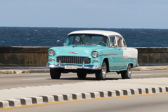 Vintage turquoise classic car driving along the Malecón in Havana, Cuba