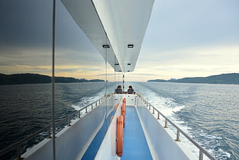 Two people on a boat deck with ocean and islands