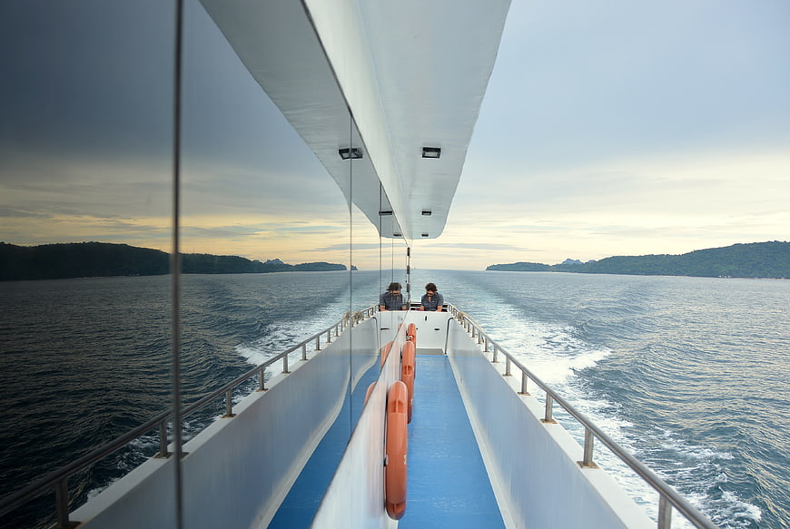 Two people on a boat deck with ocean and islands