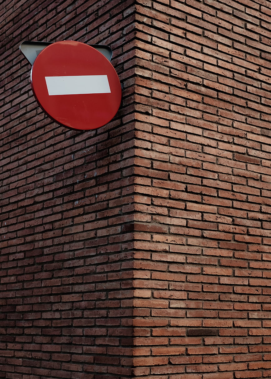 Red No Entry Sign on Textured Brick Wall Corner