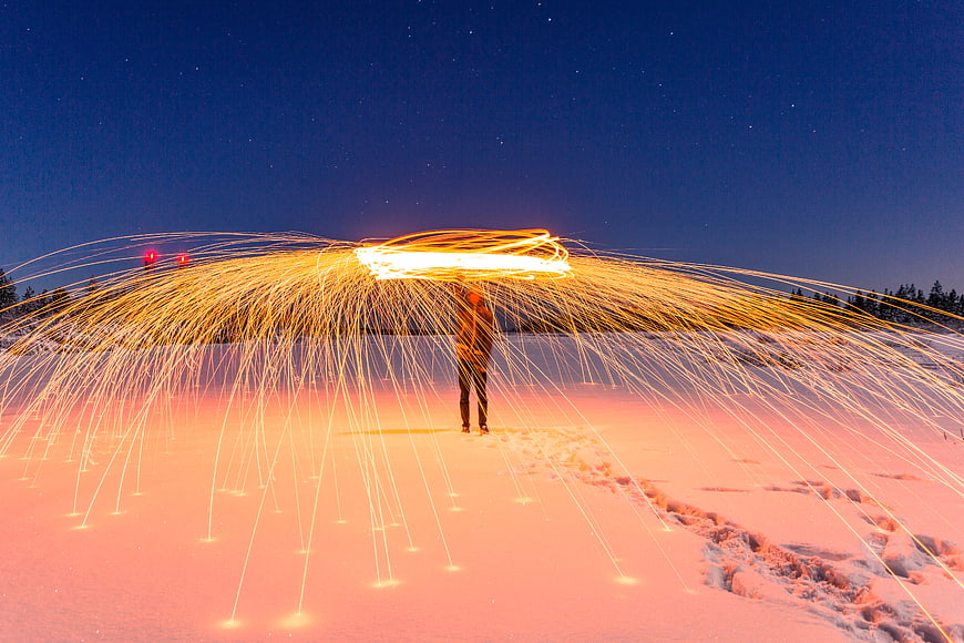 Man Spinning Steel Wool Fire in Snowy Night Landscape