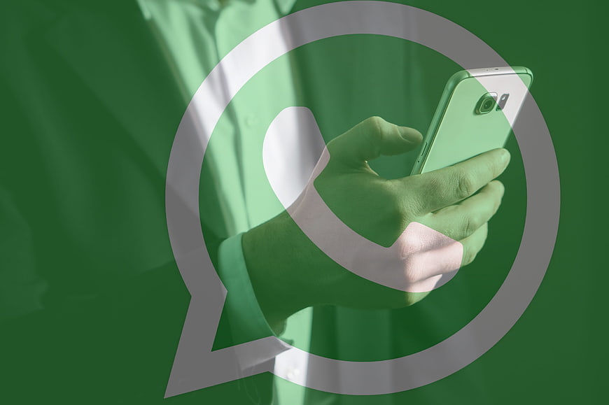 Hand holding smartphone with WhatsApp logo overlay