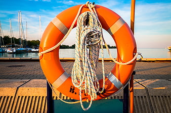 Orange Lifebuoy With Rope On Marina Pier At Sunset