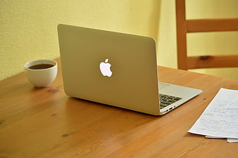 Silver laptop with coffee cup and handwritten notes on wooden table