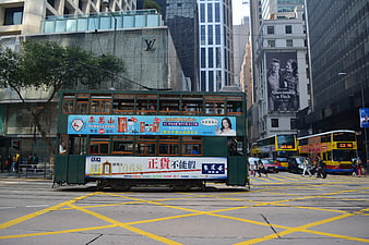 Green double-decker tram crossing a busy urban intersection in Hong Kong