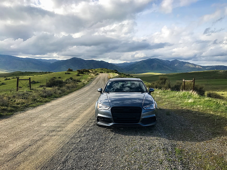 Gray Audi Sedan on Gravel Road in Mountain Landscape