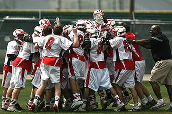 Lacrosse team huddle celebrating with coach on field
