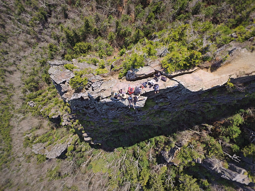 Aerial view of hikers resting on a rocky cliff edge