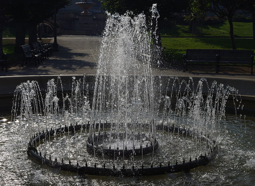 Sparkling water fountain in a sunny park with benches