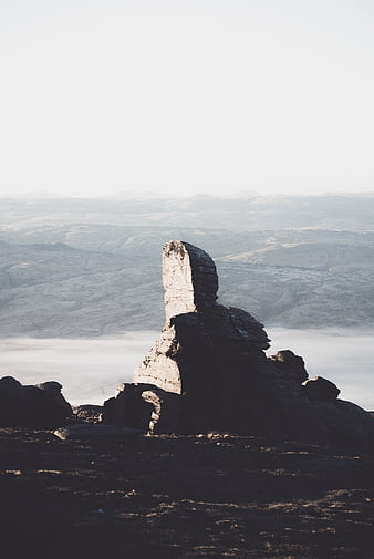 Dramatic rock formation on misty mountain ridge at sunrise