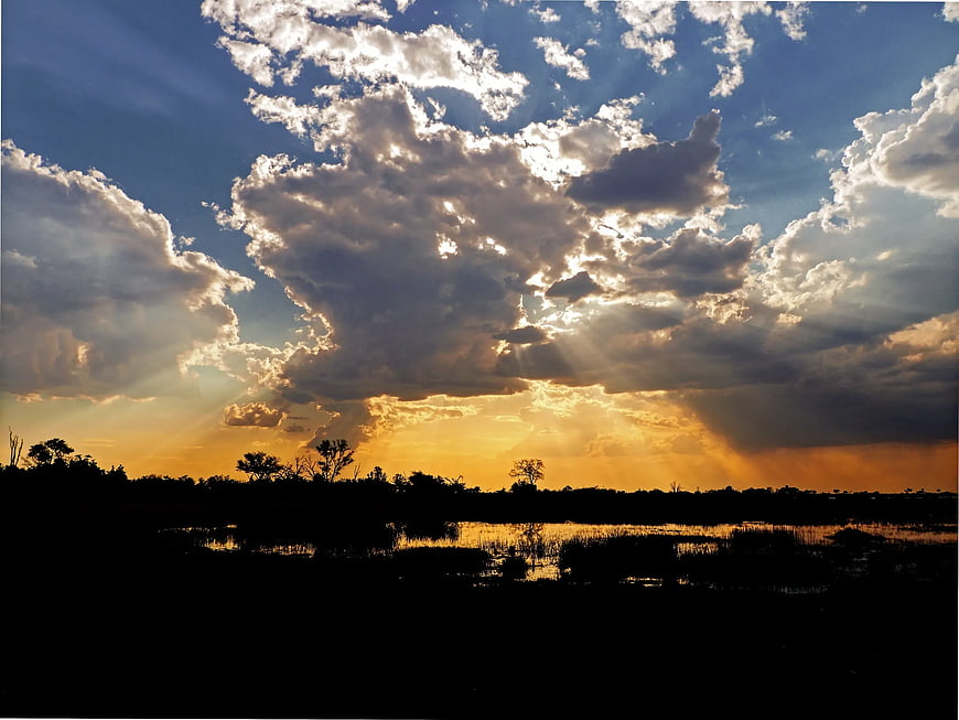 Dramatic sunset with sunbeams over silhouetted wetlands