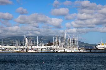 Marina with sailboats and yachts under a cloudy blue sky