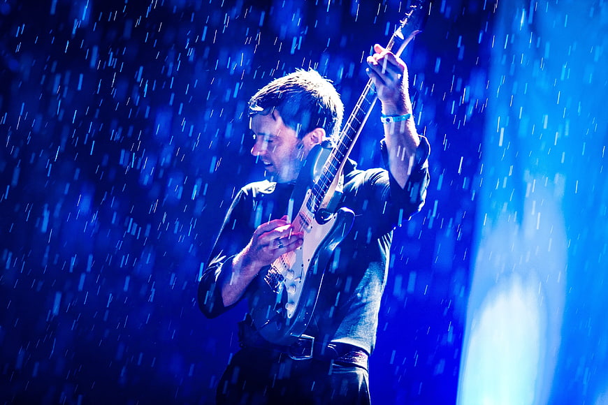 Male Guitarist Performing on Stage in Blue Light