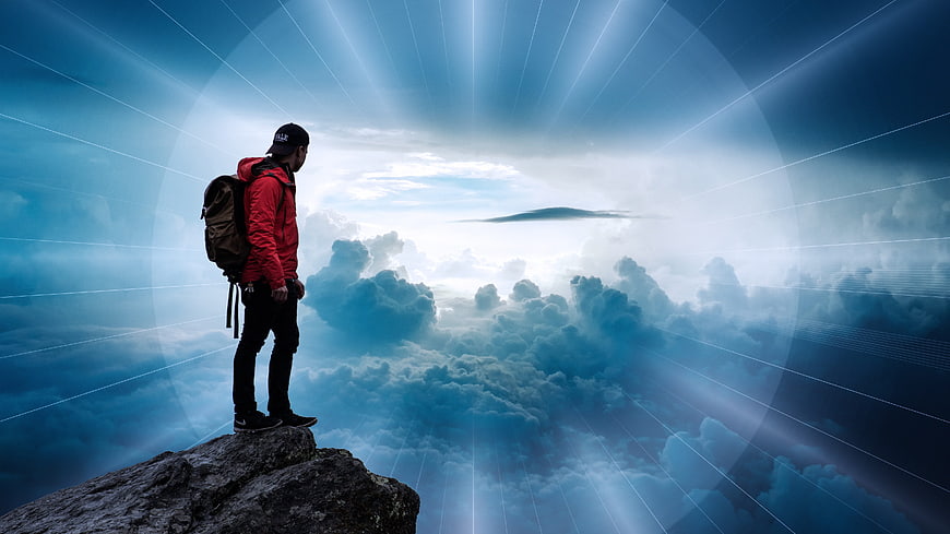 Hiker on Cliff Edge Looking at Clouds and Light Rays