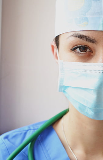 Close-up portrait of female surgeon in blue scrubs and mask