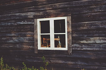 White window on weathered dark wooden cabin wall