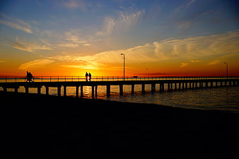 Silhouetted Couple Walking on Pier at Sunset