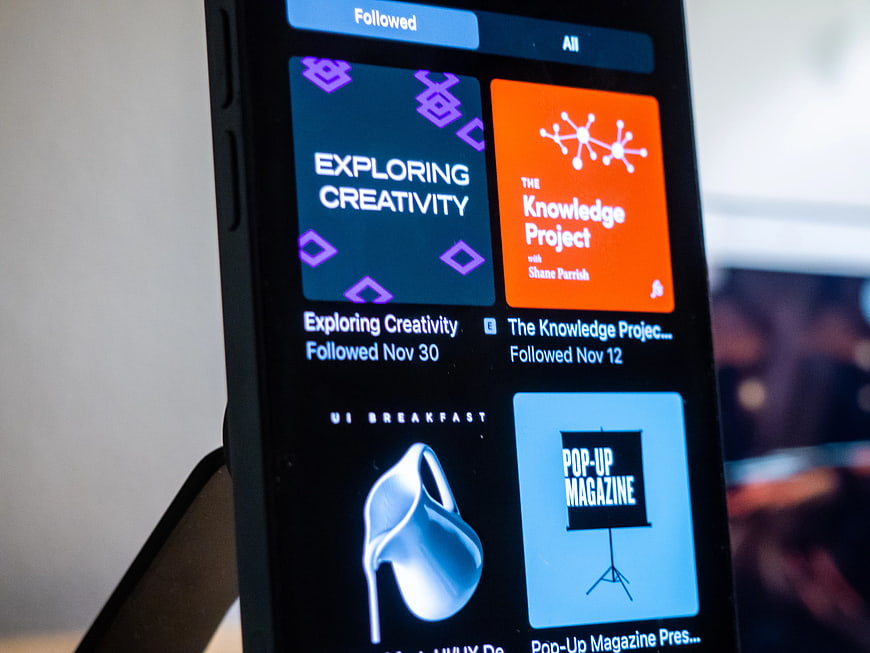 Smartphone displaying podcast app interface with colorful album art