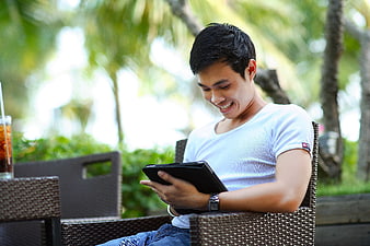 Happy Asian Man Using Tablet at Outdoor Cafe