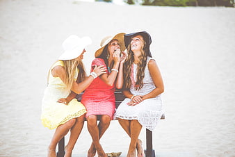 Three happy women laughing together on a beach bench