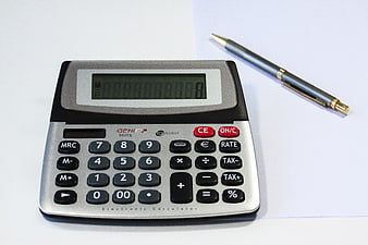 Silver desktop calculator with pen on white paper
