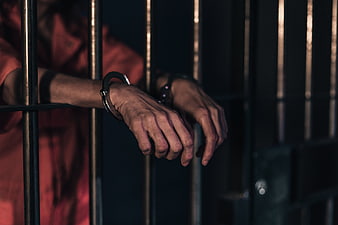 Handcuffed Prisoner Behind Bars