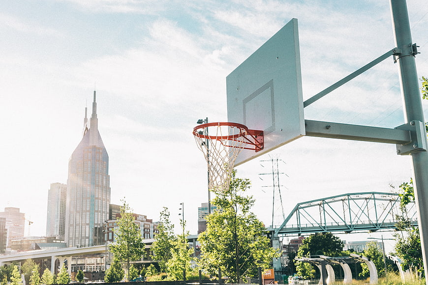 Outdoor basketball hoop with city skyline and bridge background