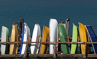 Colorful Rowboats Stored on Wooden Dock by Blue Sea