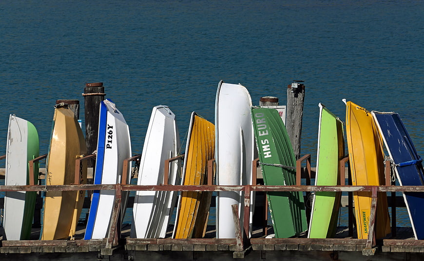 Colorful Rowboats Stored on Wooden Dock by Blue Sea