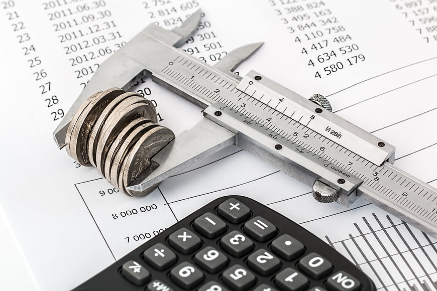 Vernier caliper measuring stack of coins on financial report