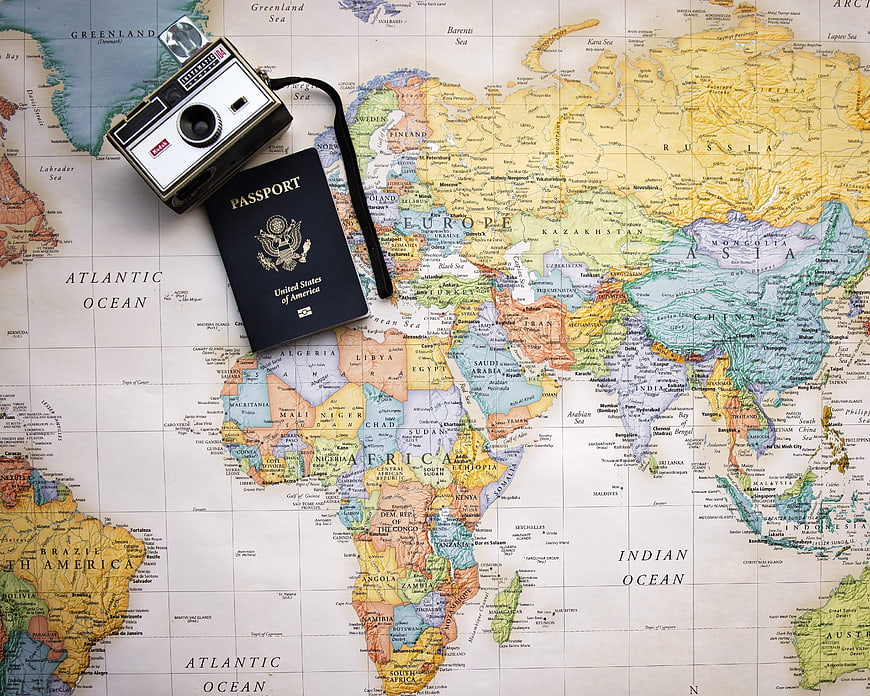 Vintage camera and passport on world map for travel planning