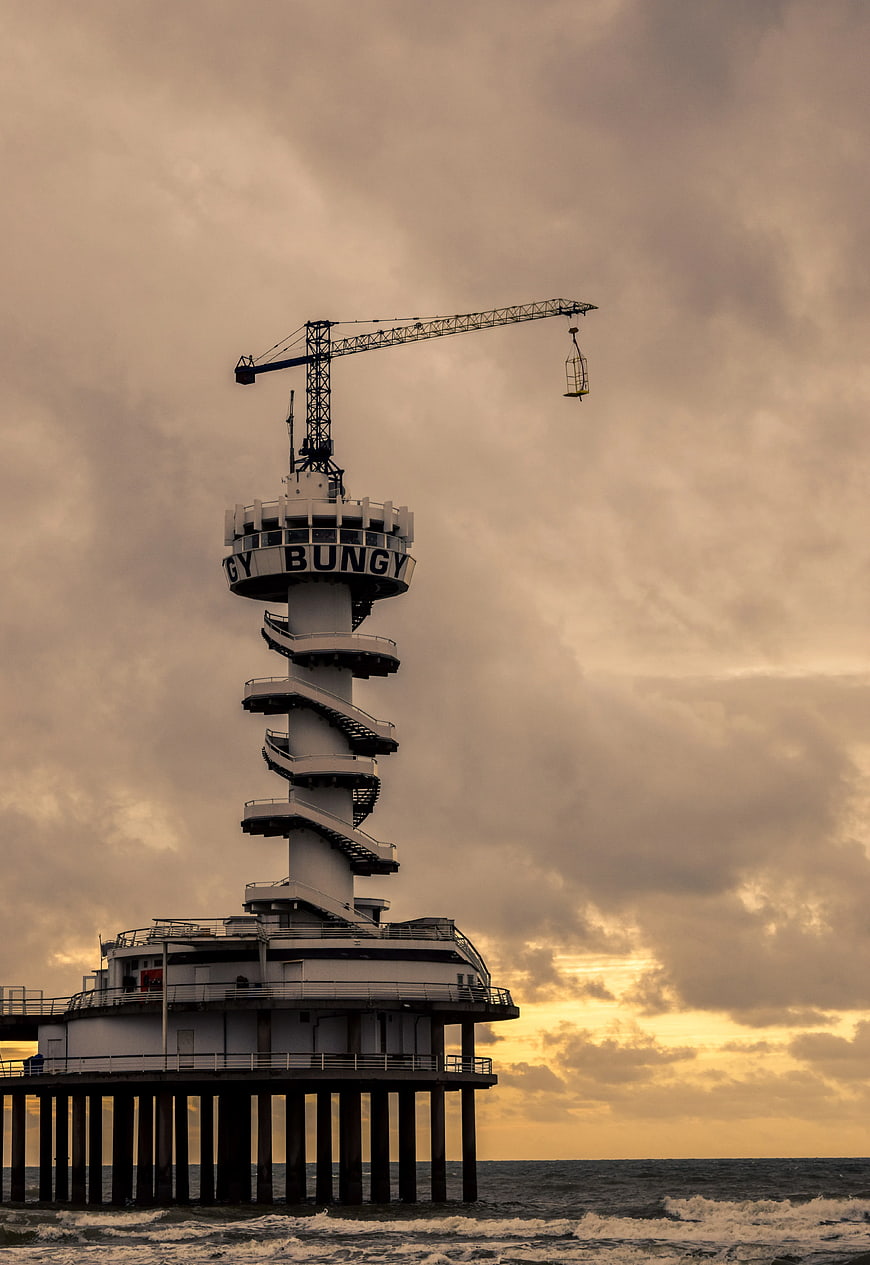 White Spiral Tower on Pier with Crane at Sunset