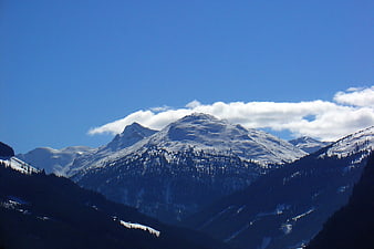 Snowy mountain peak with clouds against blue sky