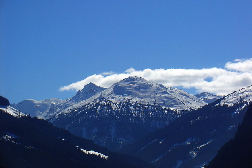 Snowy mountain peak with clouds against blue sky