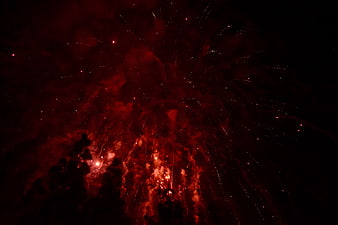 Red fireworks exploding in night sky with smoke