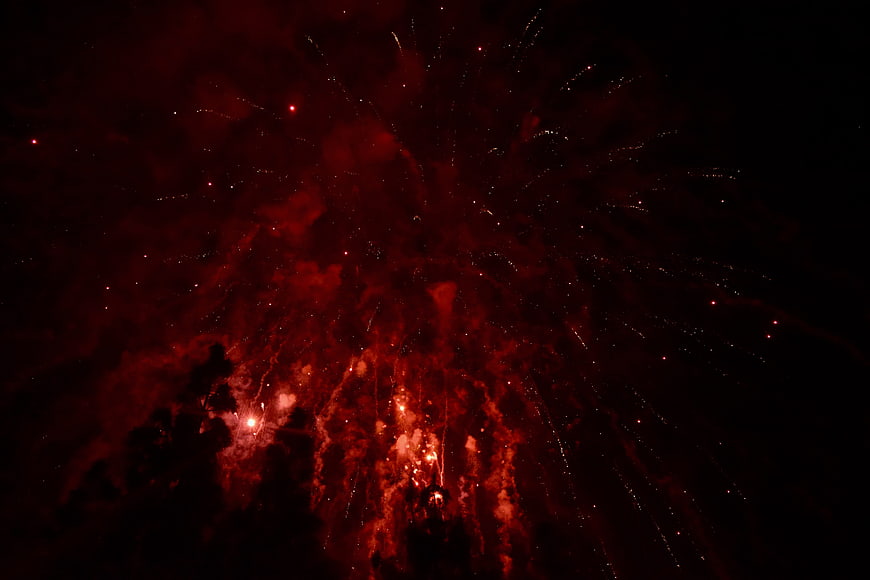 Red fireworks exploding in night sky with smoke