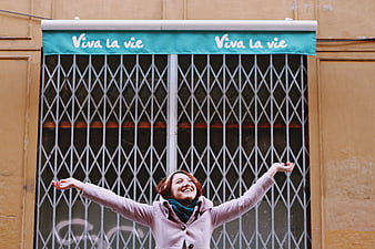 Happy woman with arms raised in front of Viva la vie awning