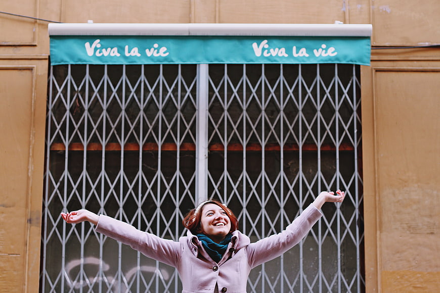 Happy woman with arms raised in front of Viva la vie awning