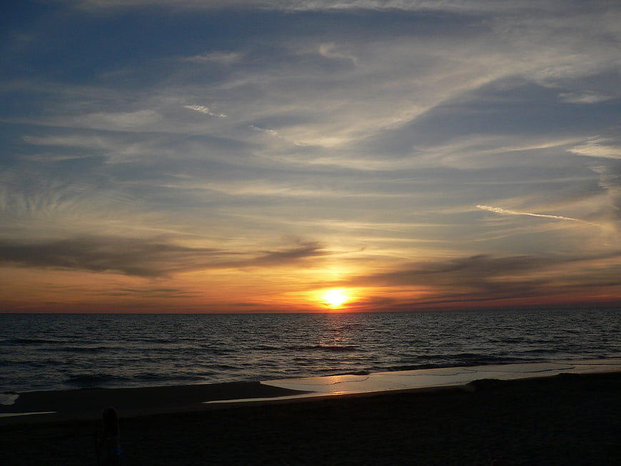Serene sunset over calm ocean with silhouetted beach